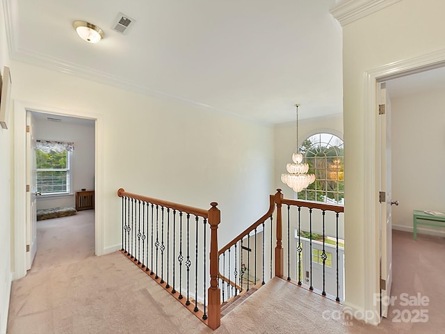 hall featuring crown molding, light carpet, and a notable chandelier