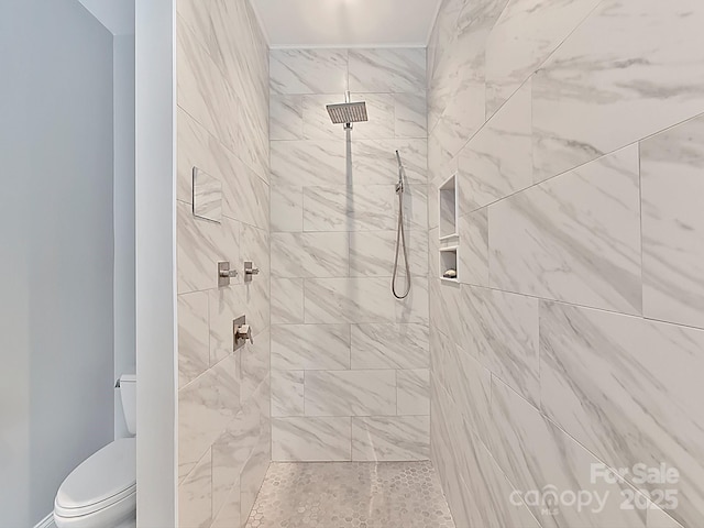 bathroom with toilet and a tile shower