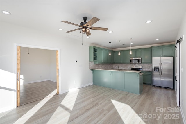 kitchen with pendant lighting, kitchen peninsula, green cabinets, light wood-type flooring, and stainless steel appliances