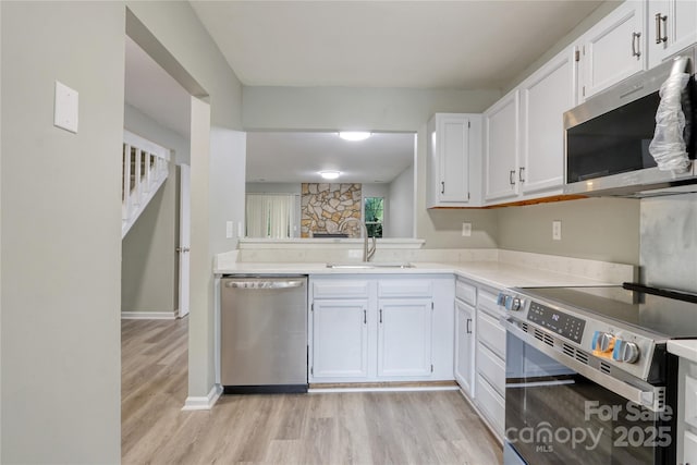 kitchen with sink, stainless steel appliances, light hardwood / wood-style flooring, and white cabinetry