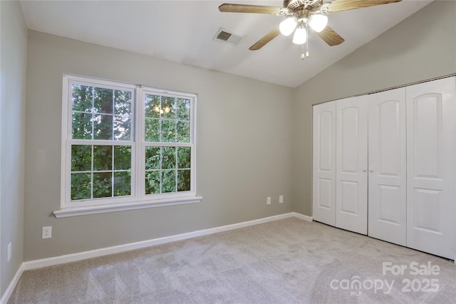 unfurnished bedroom with lofted ceiling, a closet, ceiling fan, and light carpet