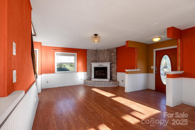 unfurnished living room featuring a brick fireplace and hardwood / wood-style floors