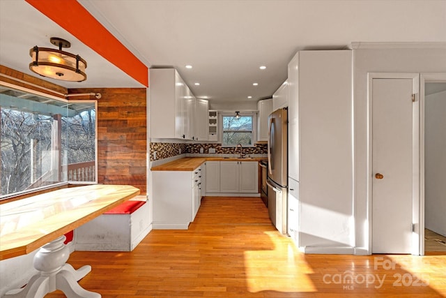 kitchen featuring wood counters, white cabinetry, stainless steel fridge, backsplash, and sink