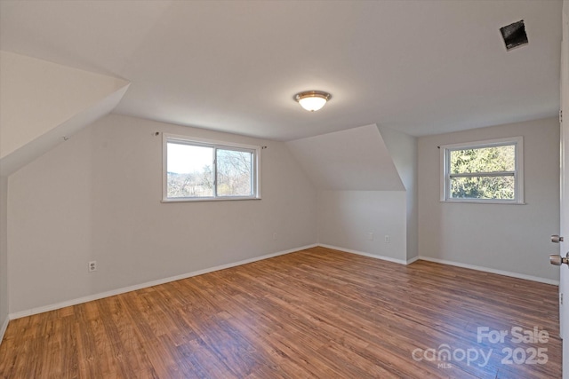 additional living space with hardwood / wood-style floors and vaulted ceiling