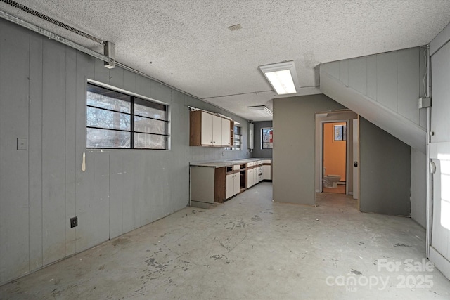 interior space featuring a textured ceiling and wood walls