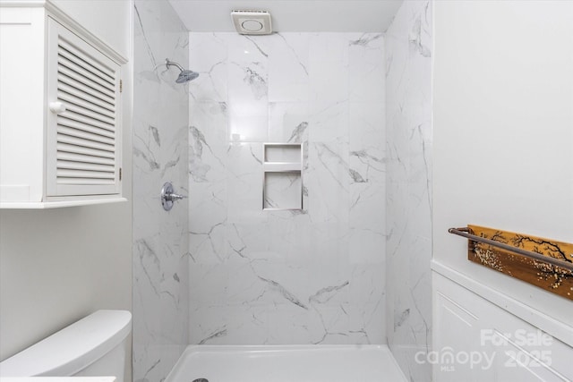 bathroom with toilet and a tile shower