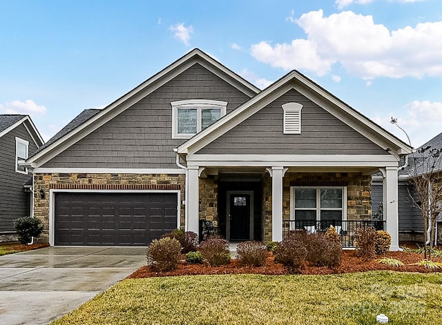 craftsman-style house featuring a garage, covered porch, and a front lawn