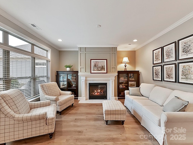 living room with ornamental molding, a fireplace, and light hardwood / wood-style floors