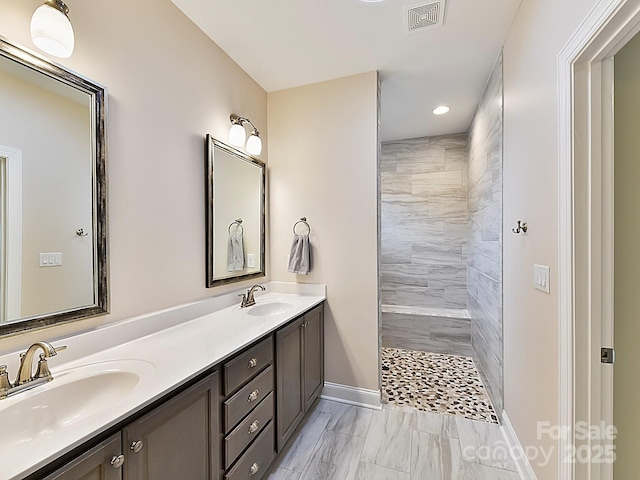 bathroom featuring tiled shower and vanity