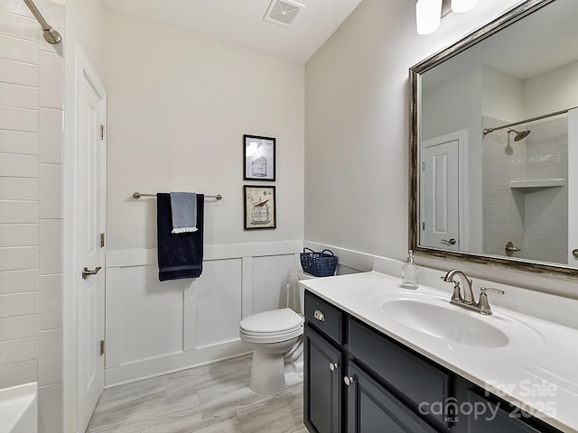 bathroom featuring vanity, toilet, and tiled shower