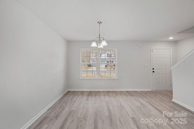 unfurnished dining area with light wood-type flooring and an inviting chandelier