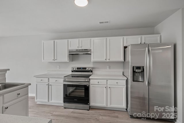 kitchen featuring appliances with stainless steel finishes, light hardwood / wood-style flooring, and white cabinetry