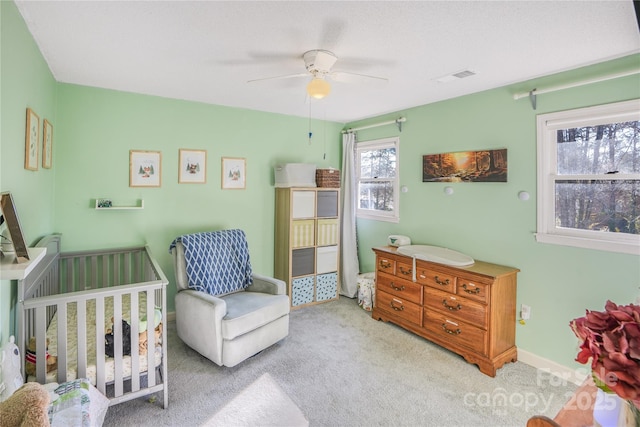 carpeted bedroom featuring ceiling fan and a crib