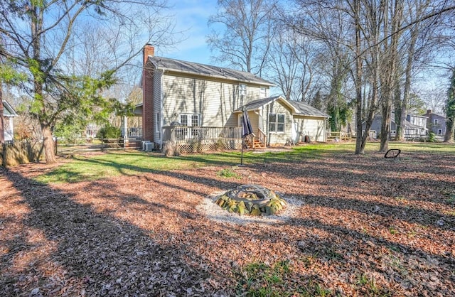 rear view of house featuring central air condition unit and a fire pit