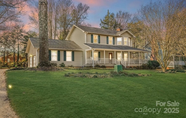 view of front of house with a lawn, a porch, and a garage