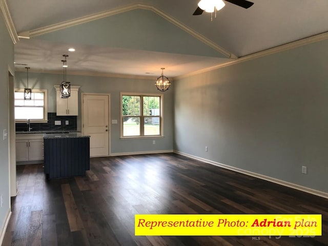 kitchen featuring ornamental molding, vaulted ceiling, hanging light fixtures, and white cabinetry