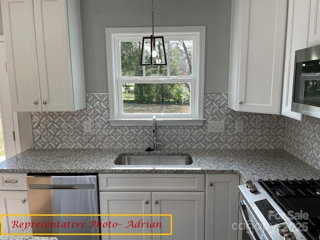 kitchen featuring white cabinets, stainless steel appliances, light stone countertops, decorative backsplash, and sink