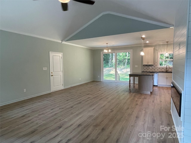 305 General As Johnston St, Stanley, NC 28164 - unfurnished living room featuring lofted ceiling, plenty of natural light, ceiling fan, crown molding, and wood finished floors