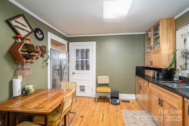 kitchen with ornamental molding, stainless steel fridge with ice dispenser, light wood-type flooring, and sink