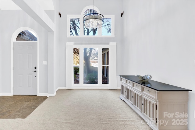 foyer featuring a notable chandelier, carpet, and a high ceiling