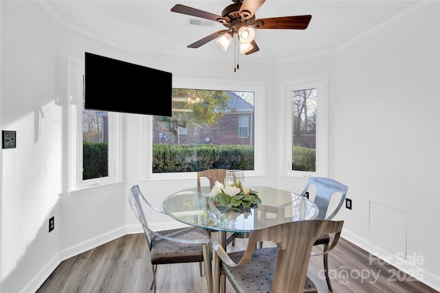 dining space with wood-type flooring, ceiling fan, and crown molding