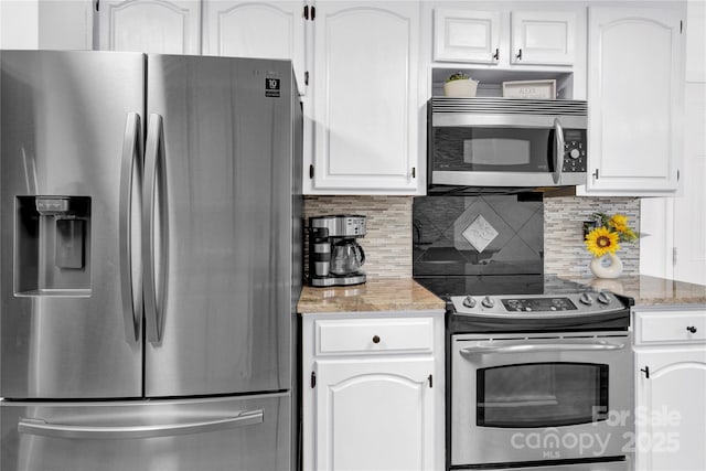 kitchen with white cabinets, decorative backsplash, dark stone countertops, and appliances with stainless steel finishes