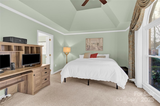 carpeted bedroom with ceiling fan and a tray ceiling