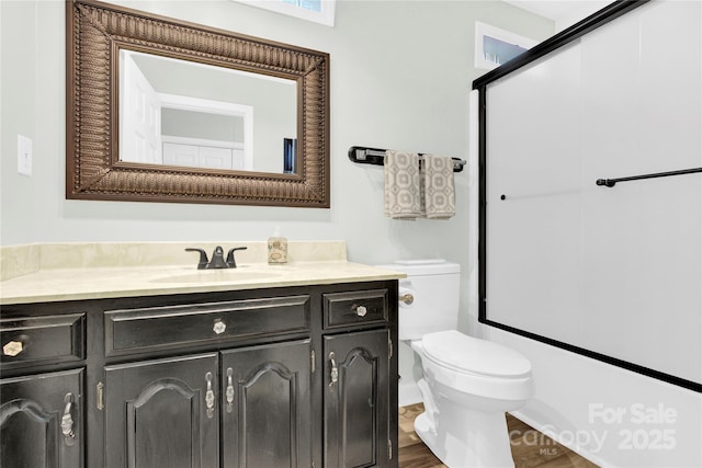 bathroom with wood-type flooring, an enclosed shower, vanity, and toilet