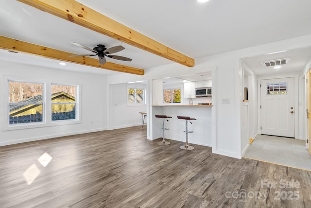 unfurnished living room featuring ceiling fan, beam ceiling, and light hardwood / wood-style floors