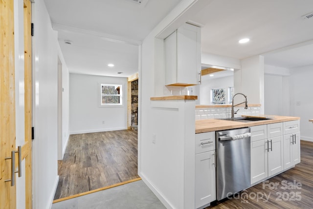 kitchen with wooden counters, decorative backsplash, dishwasher, white cabinets, and sink