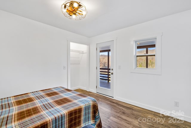 unfurnished bedroom with access to exterior, an inviting chandelier, a closet, and hardwood / wood-style flooring