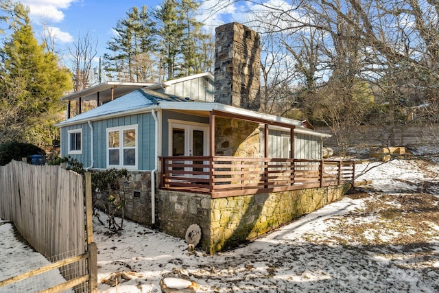 view of snowy exterior with french doors and a wooden deck