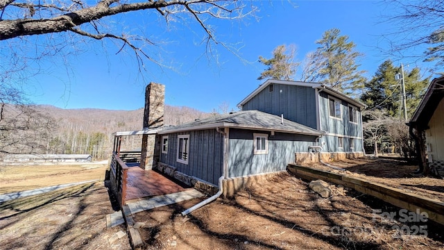 view of side of property with a chimney and a mountain view