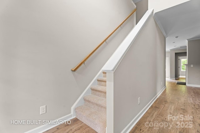 staircase featuring baseboards, ornamental molding, and wood finished floors