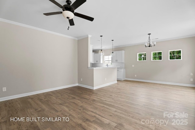 unfurnished living room with light wood finished floors, baseboards, and crown molding