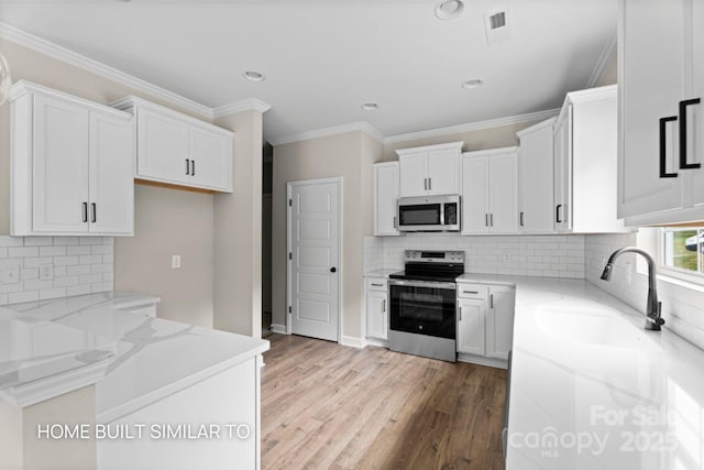 kitchen with appliances with stainless steel finishes, wood finished floors, white cabinetry, and light stone countertops