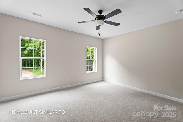 carpeted empty room featuring ceiling fan, visible vents, and baseboards