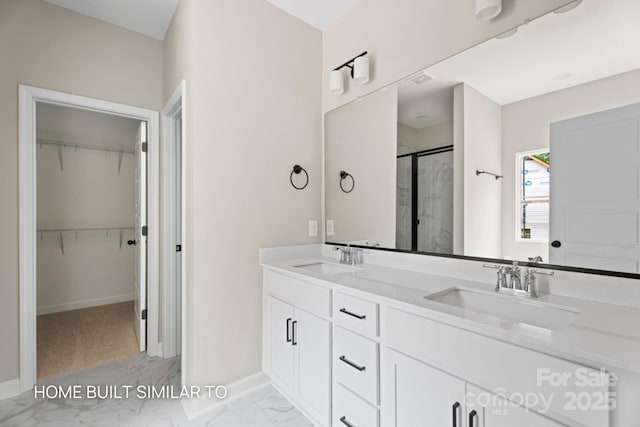 bathroom featuring marble finish floor, double vanity, a stall shower, and a sink