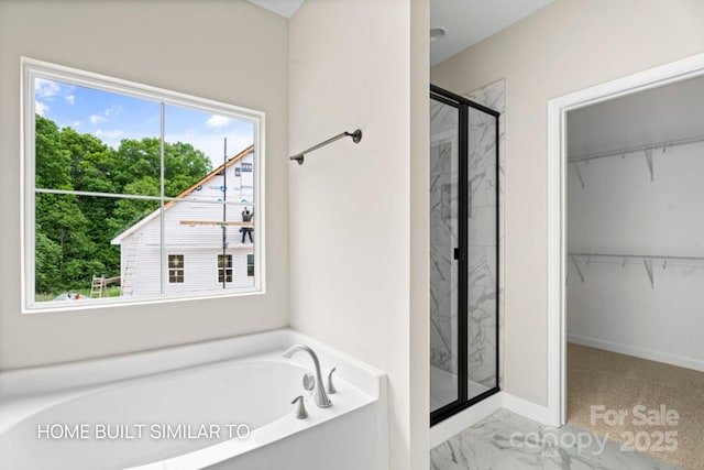 bathroom featuring marble finish floor, a garden tub, a spacious closet, a shower stall, and baseboards