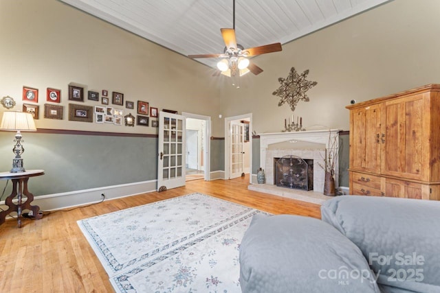 living room featuring french doors, a high ceiling, light wood-type flooring, and ceiling fan