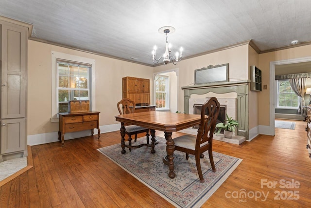 dining space with a healthy amount of sunlight, light hardwood / wood-style flooring, crown molding, and a notable chandelier