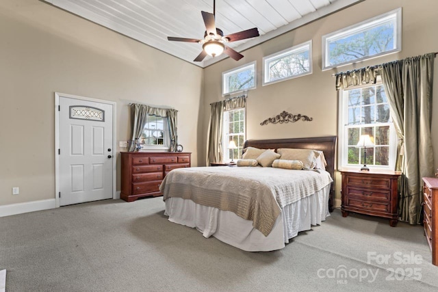 bedroom featuring a high ceiling, ceiling fan, and light carpet