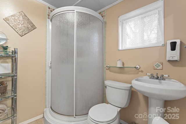 bathroom featuring toilet, a shower with door, sink, and ornamental molding