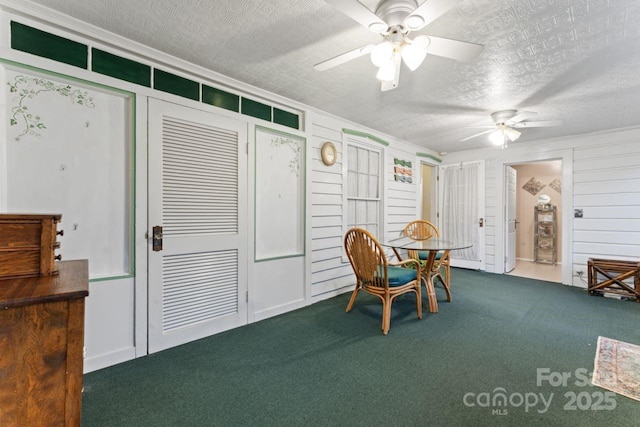 carpeted dining area featuring a textured ceiling, ornamental molding, and ceiling fan