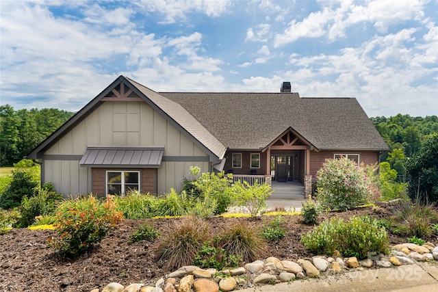 view of front of home with a chimney, roof with shingles, a standing seam roof, covered porch, and board and batten siding