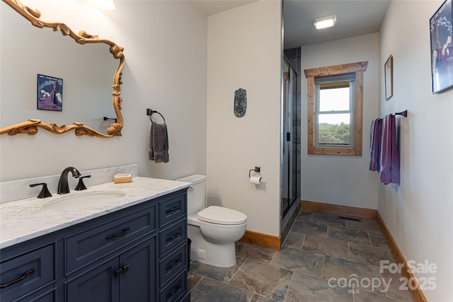 bathroom featuring a stall shower, stone finish floor, baseboards, and toilet