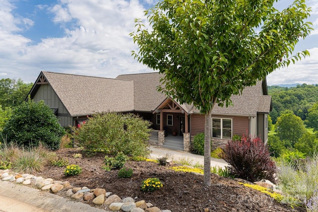 view of front of property featuring stone siding, a porch, board and batten siding, and roof with shingles