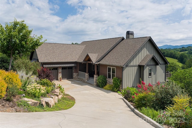 view of front of home with a chimney, a shingled roof, board and batten siding, a garage, and driveway