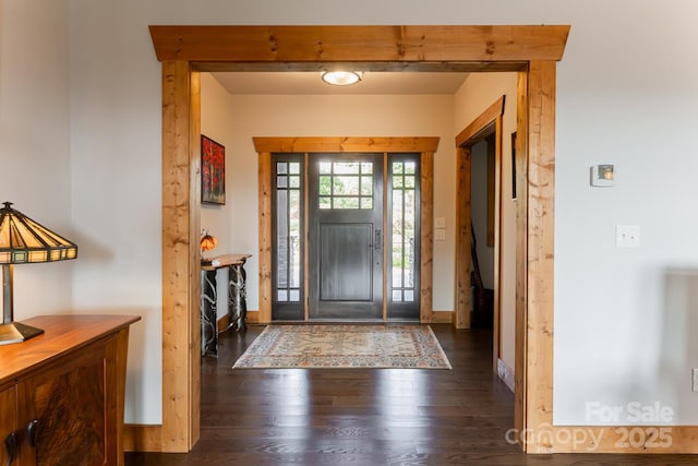 foyer with dark wood finished floors and baseboards