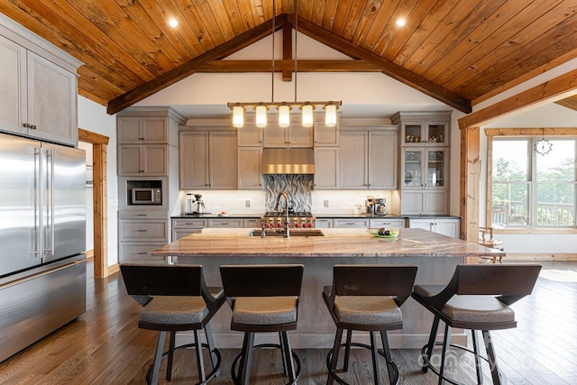 kitchen with dark wood-style floors, decorative backsplash, appliances with stainless steel finishes, a sink, and under cabinet range hood